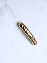 Broche dorado para el cabello con diseño texturizado.