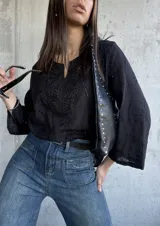 Blusa negra con bordado tipo broderie, escote en V y mangas 3/4.