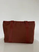 Bolso tote negro de lona con apliques de cuero y doble asa de mano.