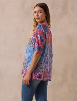 Blusa de modal estampado con flores en tonos azules, rosas y amarillos, marca Ruby Rd. Tiene cuello redondo, manga corta con abertura y apliques de brillos en el frente.