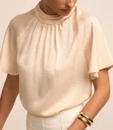 Blusa de mangas cortas confeccionada en chiffon color crema, con cuello alto, cavas raglán, cierre por gota y textura rayada.