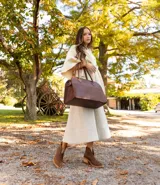 Bolso tipo tote de cuero negro con textura tipo piel de cocodrilo, doble asa de mano y cierre superior con cremallera.