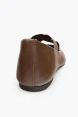 Zapato tipo bailarina plana color marrón, confeccionado en piel. Presenta tiras elásticas cruzadas en la parte delantera y acabado en punta redonda.