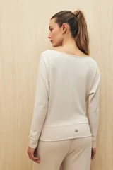 Buzo color beige de calce fluido, con cuello bote y mangas murciélago.