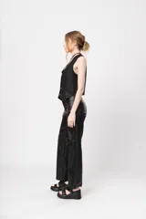Pantalón de tiro alto negro de gabardina strech metalizada, con bolsillos y cierre frontal con cremallera y botón.