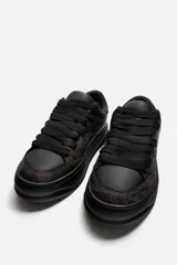Zapatillas negras con estampado animal, de cordones y suela gruesa.