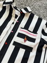 Camisa oversize de jean rayado blanco y negro con bolsillo con bordado de corazón con fuego y botones de acrílico en forma de corazón.