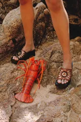Sandalias de cuero color marrón con plataforma y detalle de aplique metálico dorado en forma de sol.