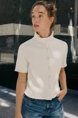 Chaqueta azul marino de punto con cuello subido y manga corta. Cierre frontal con botones.