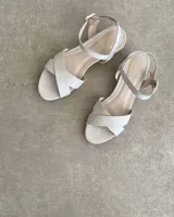 Sandalias bajas negras con tiras finas cruzadas y tobillera con hebilla.