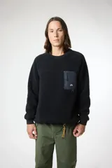 Buzo de cuello redondo confeccionado en tejido tipo polar de color negro. Presenta un diseño de mangas raglán y un bolsillo de parche en el pecho en tela técnica contrastante con cierre de cremallera vertical y etiqueta de la marca. Posee puños y cuello acanalados.