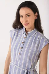 Vestido camisero de lino a rayas celestes y blancas, con cuello clásico, botones de madera y cinturón de lazo.