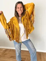 Campera de gamuza sintética color azul con flecos largos en mangas y espalda, corte recto con solapas clásicas.