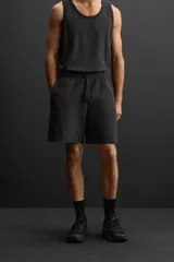 Bermuda jogger negra confeccionada en tejido de algodón con interior de rizo, cintura elástica ajustable con cordón y bolsillos laterales.