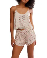 Conjunto de pijama color crema con estampado de flores rojas, compuesto por un top de tirantes con escote redondo y shorts a juego. Ambos tienen detalles de encaje en los bordes.