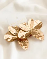 Aros colgantes dorados con forma de flor y textura martillada.