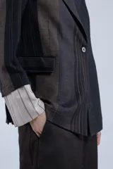 Blazer con diseño a rayas verticales en tonos marrón, gris y negro. Tiene corte recto, solapas clásicas y cierre con un botón.