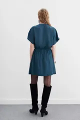 Vestido mini negro con escote cruzado, mangas cortas y cintura elastizada con lazo. Presenta cadenas metálicas en los hombros y en la terminación del lazo.