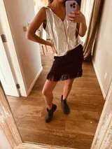 Minifalda negra tejida en lurex plateado, con flecos en el ruedo y cintura elástica.