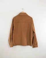 Camisa de pana color beige, de manga larga, con cuello camisero, cierre frontal de botones y dos bolsillos de parche con solapa en el pecho. Presenta un corte recto y holgado.