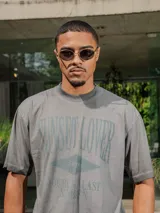 Remera de jersey con efecto teñido y corte holgado. Presenta una estampa frontal con el texto 'Sunset Lover' y 'You're my last sunburn' en color verde.