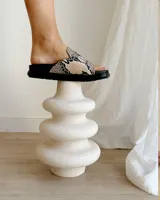 Sandalias chatas color beige con base negra y detalle de bordado blanco en la tira superior.