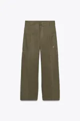 Pantalón cargo color verde oliva, de tiro alto y corte amplio. Presenta bolsillos de plastrón en pierna y espalda, trabillas en la cintura y cierre frontal con cremallera, botón interior y gancho metálico.
