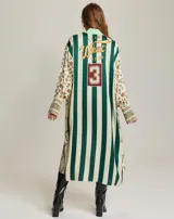 Vestido camisero midi con estampado de motivos ecuestres en tonos beige, marrón y rojo. Cuello camisero con estampado geométrico en blanco y negro. Manga larga con puños anchos con estampado geométrico en blanco y negro.