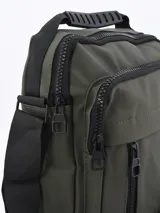 Bandolera verde militar con correa ajustable negra, cierre superior y bolsillos frontales con cremallera.