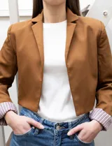 Blazer crop color marrón, marca Dictionary. Cuello con solapa, manga larga y forro interno estampado a rayas.