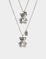 Set de dos collares plateados con dije de oso y corazón de cristal.