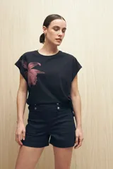 Remera blanca de manga corta con estampado de una flor color durazno en el frente.