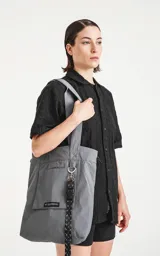 Bolso tipo tote bag de microfibra técnica color gris, con cordón ajustable con tanca. Posee un bolsillo externo con velcro y un bolsillo interno con cierre.