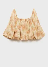 Blusa corta de gasa color crema con estampado floral en tonos durazno y verde. Tiene escote cuadrado, mangas largas abullonadas y espalda abierta.