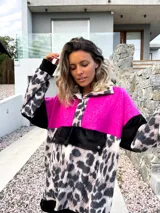 Buzo de corte amplio con bloques de color fucsia, negro y estampado animal print de leopardo en tonos beige y negro. Tiene cuello alto con cierre de botones a presión y bolsillo tipo canguro con botones a presión.