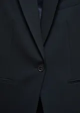 Blazer negro entallado con solapas de muesca, hombros estructurados, abertura posterior y dos bolsillos de ribete delanteros.