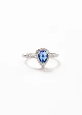 Anillo de plata 925 con una gema azul central rodeada de pequeñas zirconias. El cuerpo del anillo también está adornado con zirconias.