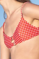 Top de bikini rojo con estampado de cuadros blancos, breteles finos y argollas metálicas en el centro del busto.