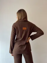 Conjunto de sweater y pantalón acampanado de punto acanalado color chocolate. El sweater es de corte holgado con cierre de media cremallera.