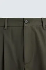 Pantalón verde oliva de corte amplio con pliegues en la parte delantera, bolsillos laterales y traseros de ojal.