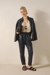Pantalón babucha de cuero ovino color negro, con bolsillos en el frente, cintura elastizada y tira de ajuste con terminales metálicas.