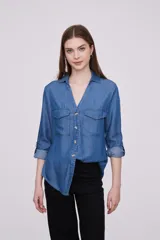 Camisa celeste de lyocell, con cuello clásico, cierre frontal con botones, mangas largas con puños abotonados y dos bolsillos con solapa en el pecho.