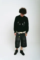 Bermuda de jean negro con lavado ácido gris, corte baggy y bolsillos grandes. Presenta bordados plateados y blancos, cierres y botón personalizado.