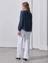 Blusa azul marino de manga larga con cuello redondo con detalle de broderie y cierre frontal con botones.