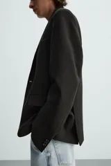 Blazer azul marino de corte recto, confeccionada en tejido con viscosa. Tiene cuello con solapas de muesca, manga larga con puño abotonado, bolsillo de vivo en el pecho y bolsillos de parche en la cadera. El bajo tiene aberturas en la espalda y el cierre es con botonadura frontal.