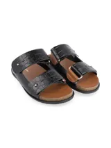 Sandalias negras con textura de piel de cocodrilo, dos tiras anchas sobre el empeine con hebillas plateadas y plantilla de corcho.