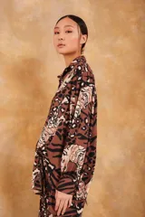 Camisa marrón con estampado de tigres y manchas de leopardo, de corte holgado y mangas largas.