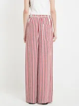 Pantalón de viscosa con rayas verticales rojas y blancas, corte recto, cintura elástica con cordón decorativo.