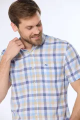 Camisa de manga corta con cuello abotonado y corte slim fit. Presenta un estampado a cuadros en tonos celeste, azul y beige.