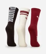 Kit de tres pares de medias deportivas Puma de caña larga. Un par color beige con dos rayas marrones horizontales en la parte superior y logo marrón en el tobillo. Un par color crema liso con logo blanco en el tobillo. Un par color marrón con una raya blanca horizontal en la parte superior y logo blanco en el tobillo.